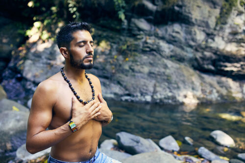 Photo of man in nature with hands on chest.